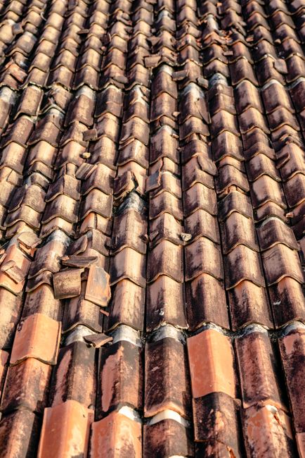 A homeowner photographs missing shingles and an indoor ceiling water stain after a storm.